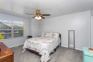 Carpeted bedroom featuring ceiling fan