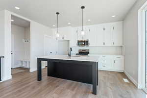 Kitchen with white cabinetry, sink, pendant lighting, an island with sink, and stainless steel appliances