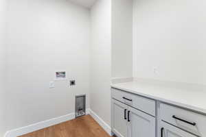 Laundry room featuring electric dryer hookup, cabinets, light hardwood / wood-style flooring, and hookup for a washing machine