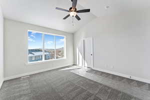 Unfurnished room with ceiling fan, carpet, and lofted ceiling