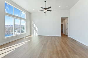 Unfurnished living room with a mountain view, ceiling fan, a high ceiling, and light hardwood / wood-style flooring