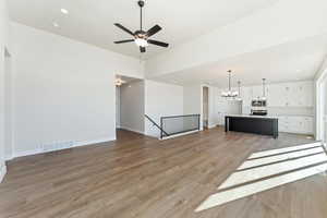 Unfurnished living room featuring hardwood / wood-style floors and ceiling fan with notable chandelier