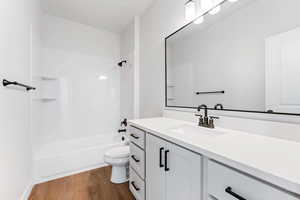 Full bathroom featuring vanity, hardwood / wood-style flooring, washtub / shower combination, and toilet