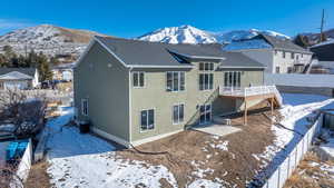 Snow covered back of property featuring central air condition unit and a deck with mountain view