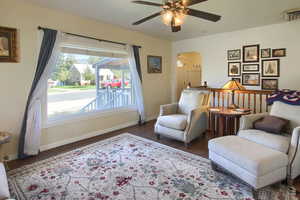 Living area with ceiling fan and dark hardwood / wood-style flooring