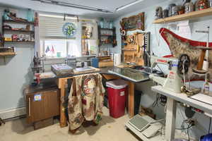 Miscellaneous room featuring a workshop area, a baseboard heating unit, and concrete floors