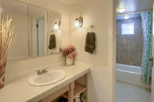 Bathroom with shower / bathtub combination with curtain and sink