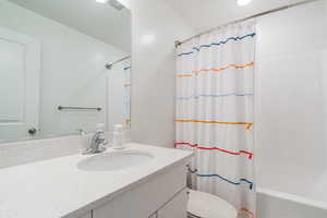 Full bathroom with vanity, toilet, and shower / bathtub combination with curtain