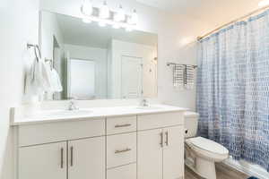 Primary bathroom with dual sinks, large mirror, and hard flooring.