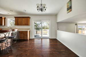 Kitchen with sink, decorative light fixtures, dark hardwood / wood-style floors, and a chandelier