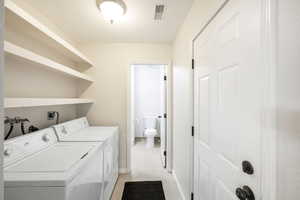 Clothes washing area with light tile patterned floors and separate washer and dryer