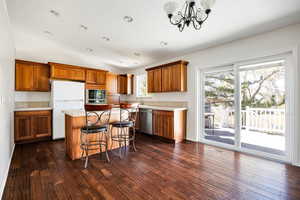 Kitchen with a kitchen island, a notable chandelier, stainless steel appliances, and a healthy amount of sunlight