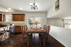 This photo is virtually staged. Dining space with a notable chandelier, a healthy amount of sunlight, and dark hardwood / wood-style flooring