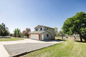 View of home's exterior with a lawn, a shed, and a garage