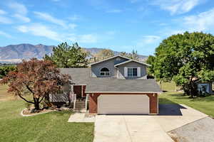 View of front of home with a front yard, a garage, and a mountain view. virtually enhanced photo.