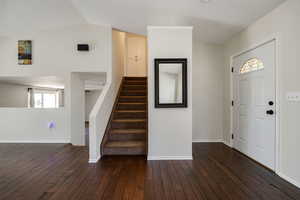 Entrance foyer with vaulted ceiling and dark wood-type flooring