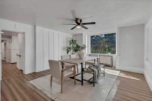 Dining space with light hardwood floors, and ceiling fan and architectural trim.