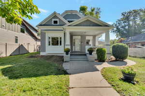 View of front of home with a front yard and covered porch.