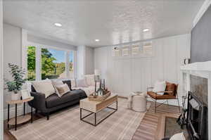 Living room with  light wood flooring, and a tiled fireplace and window seat.