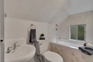 Mother-in-law Full bathroom featuring tile walls, sink, lofted ceiling, tiled shower / bath combo, and toilet