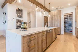 Kitchen with a large island, light hardwood / wood-style floors, sink, beam ceiling, and decorative light fixtures