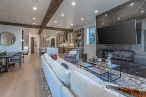 Living room featuring light hardwood / wood-style flooring, a premium fireplace, and beam ceiling