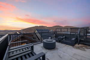 Patio terrace at dusk featuring a mountain view and a balcony