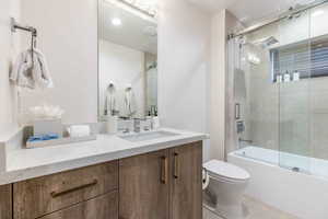 Full bathroom featuring enclosed tub / shower combo, vanity, and toilet