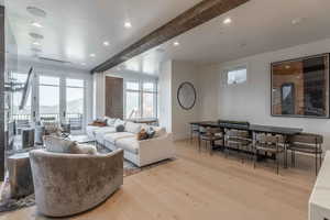 Living room with light wood-type flooring and beamed ceiling