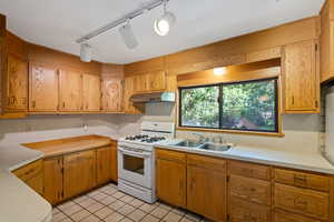 Kitchen featuring light tile patterned floors, sink, white range with gas cooktop, and rail lighting