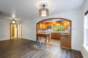 Kitchen with pendant lighting, LVP / wood-style flooring, sink, kitchen peninsula, and white appliances