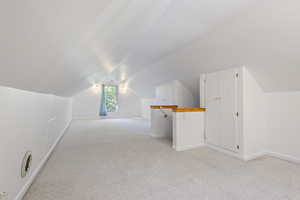 Bonus room with vaulted ceiling and light carpet