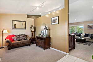 Carpeted living room with lofted ceiling and track lighting