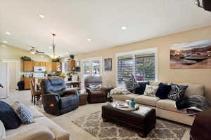 Carpeted living room with lofted ceiling and ceiling fan