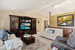 Living room with rail lighting, carpet flooring, and vaulted ceiling