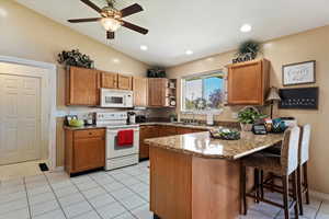 Kitchen featuring ceiling fan, kitchen peninsula, sink, white appliances, and vaulted ceiling