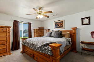 Carpeted bedroom with a textured ceiling and ceiling fan