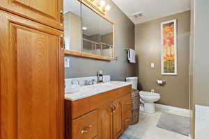 Bathroom featuring vanity, a textured ceiling, toilet, and a shower with door