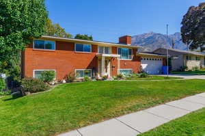 View of front of home with a mountain view, a front lawn, and a garage