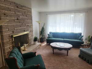 Living room with carpet floors and a stone fireplace