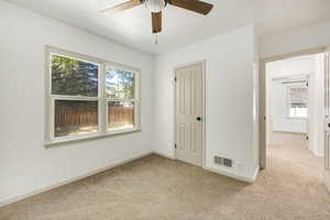 Unfurnished bedroom with ceiling fan, light carpet, and multiple windows