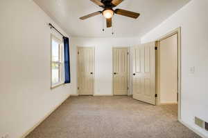 Unfurnished bedroom with light carpet, multiple closets, ceiling fan, and a textured ceiling