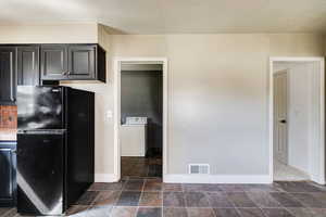 Kitchen with washer / dryer and black refrigerator