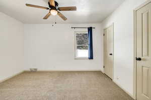 Carpeted empty room with ceiling fan and a textured ceiling