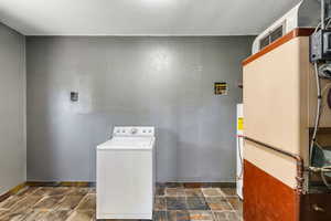 Washroom featuring washer / clothes dryer, heating unit, and gas water heater