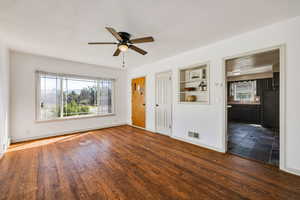 Interior space with ceiling fan, a textured ceiling, dark wood-type flooring, and built in shelves