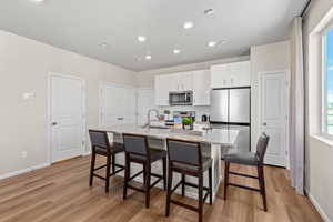 Kitchen with a kitchen breakfast bar, an island with sink, stainless steel appliances, light wood-type flooring, and sink