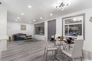 Dining room featuring a textured ceiling, light hardwood / wood-style flooring, and a notable chandelier