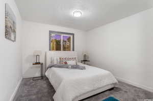 Bedroom with dark carpet and a textured ceiling