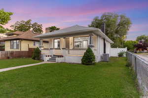 View of front of home featuring cooling unit, a porch, and a yard